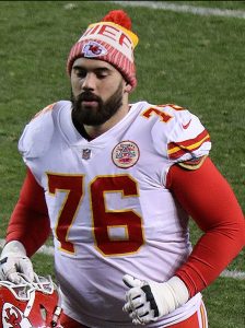 Laurent Duvernay-Tardif s'habille dans un uniforme footballeur américain pour l'équipe Kansas City Chiefs. Il est sur le champs de football et il court.